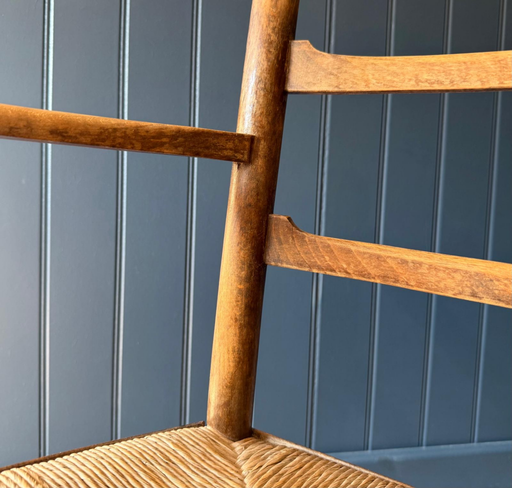 Vintage wooden woven chair against Stiffkey blue panelling, North Wales